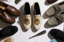 Collection of men's loafers and dress shoes with a branded box on a white background