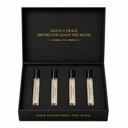 A black presentation box with gold lettering, opened to display four small cylindrical perfume or fragrance vials arranged side by side. The inside lid reads 'LEAVE A TRACE BEFORE YOU LEAVE THE ROOM.