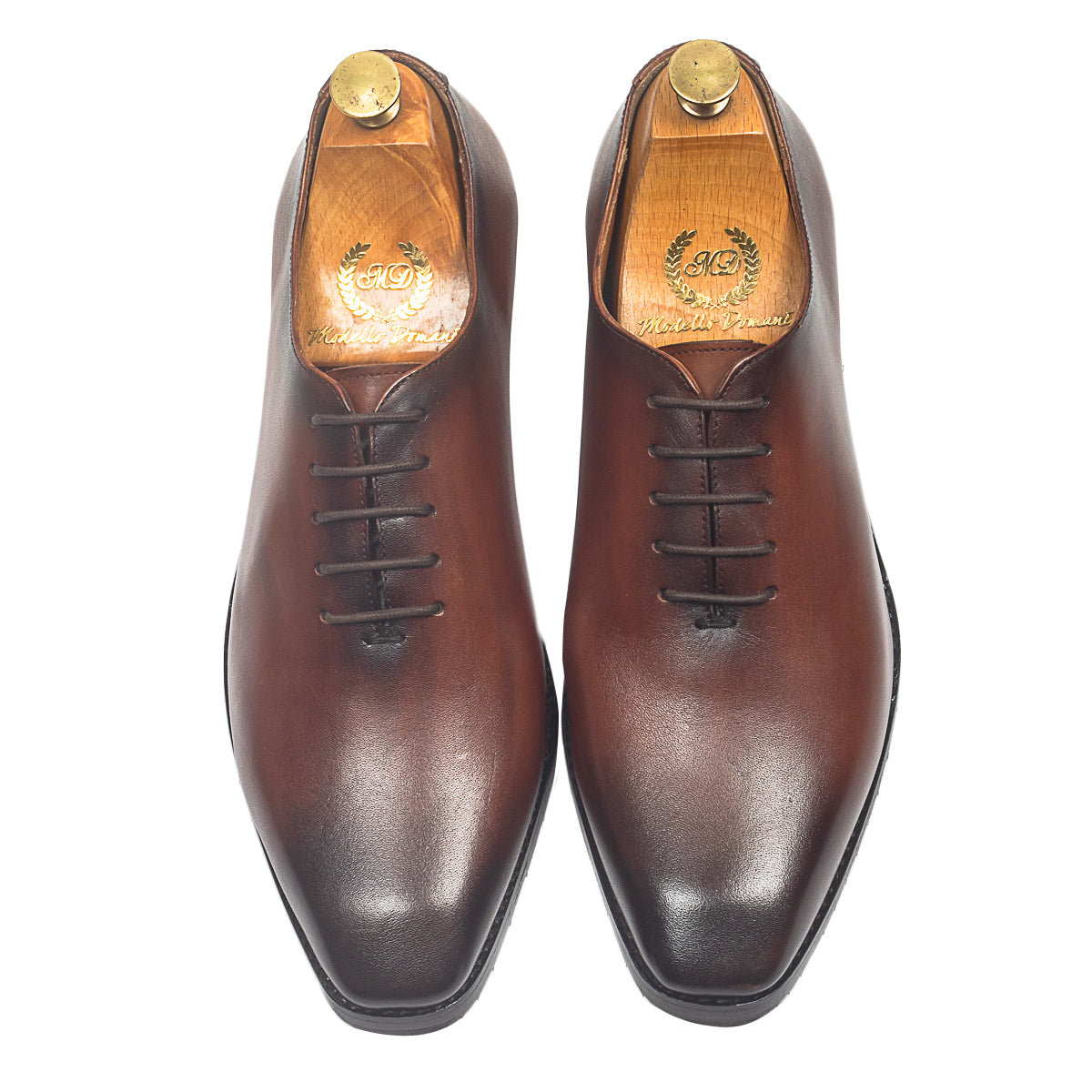Brown leather dress shoes worn with gray pants on a light background
