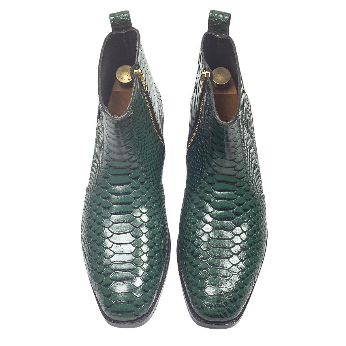Green snake-textured boots worn with black pants on a beige background