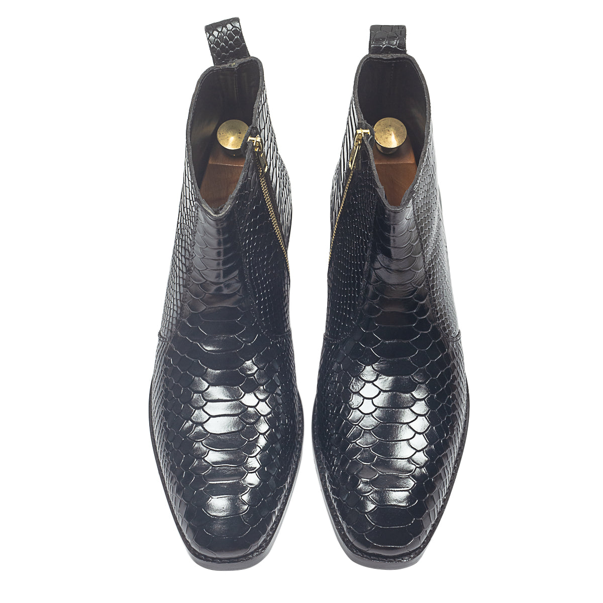 Black leather boots worn with blue jeans on a beige background