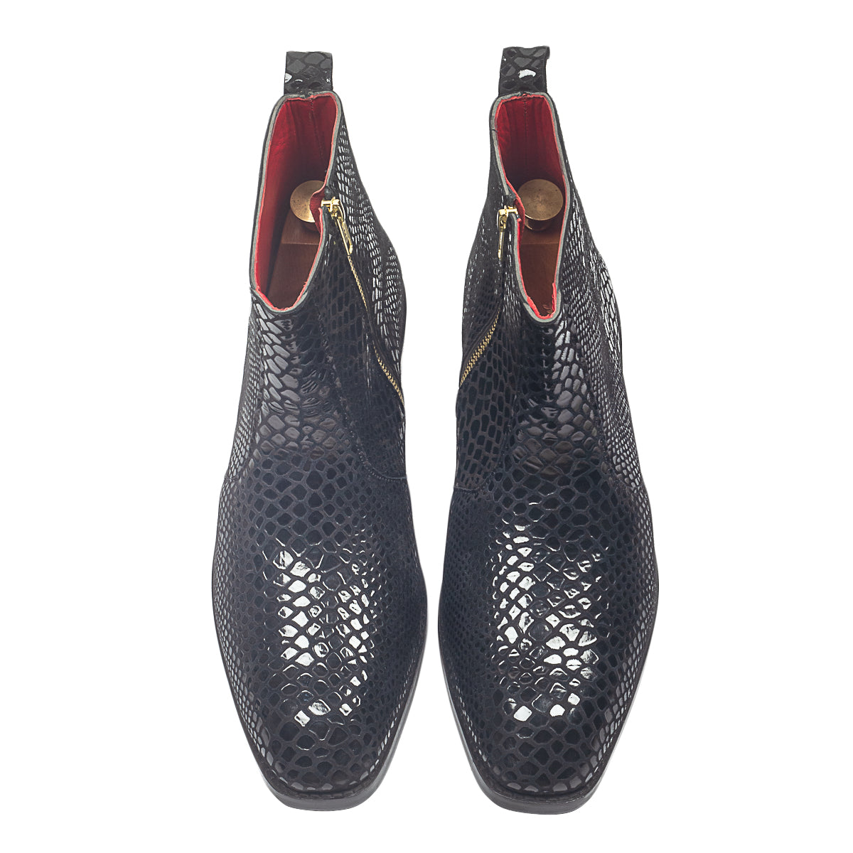 Black textured ankle boots worn with gray pants on a light wooden floor.