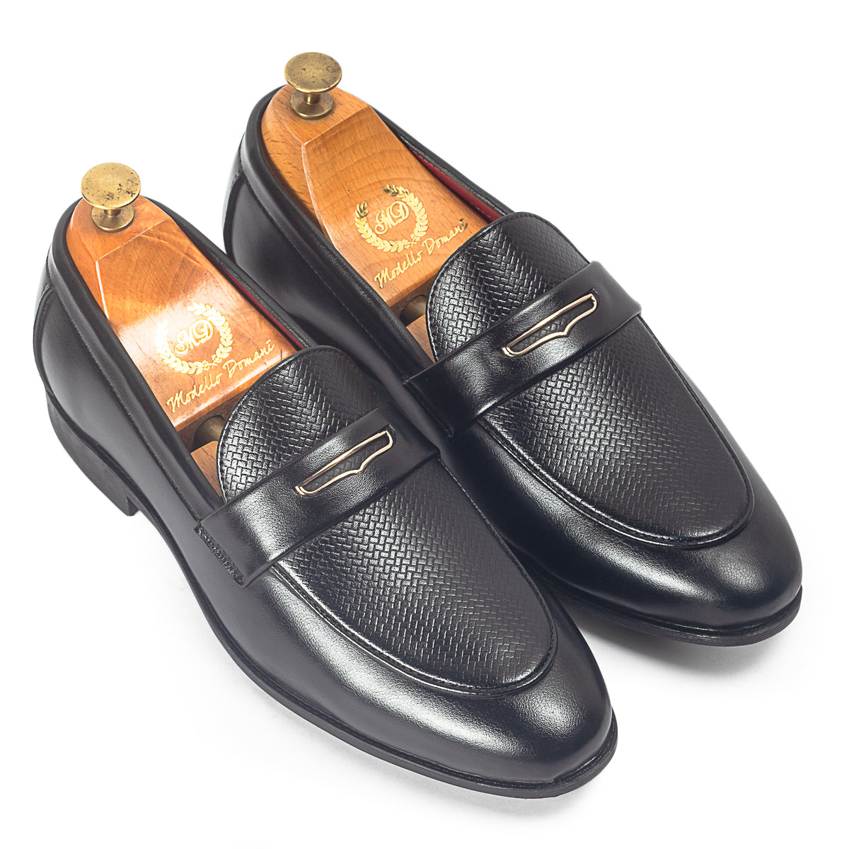 Pair of black leather loafers with gold accents on a white background