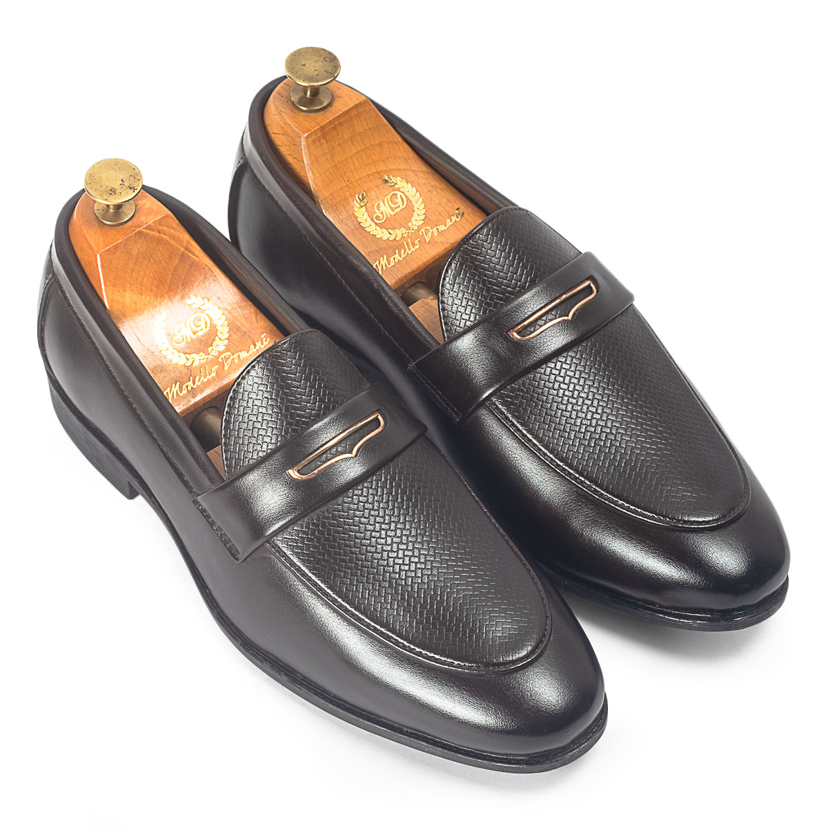 Pair of black leather loafers with gold accents on a white background