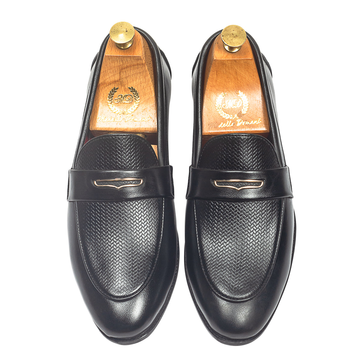 Black loafers worn with beige pants on a light background