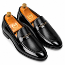 A pair of men's black leather penny loafers with a glossy patent leather toe cap and a textured woven pattern upper, displayed on wooden shoe trees against a white background.