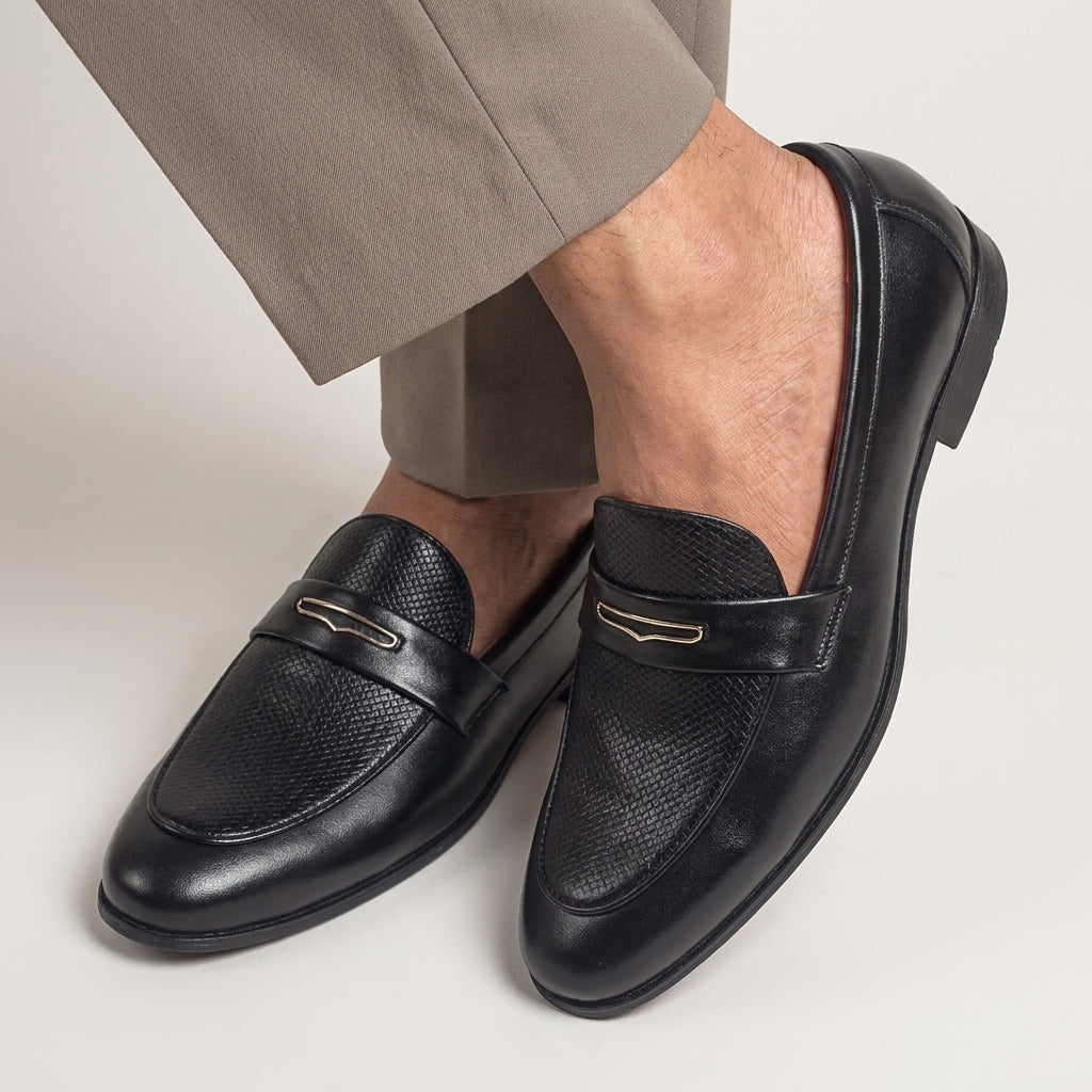 Black loafers worn with beige pants on a light background