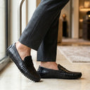 Person wearing black loafers indoors with a blurred background