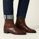 Brown textured ankle boots worn with rolled-up jeans on a neutral background