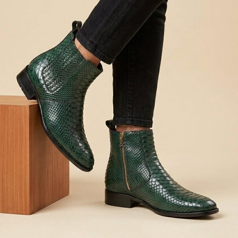 Green snake-textured boots worn with black pants on a beige background