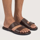 Brown sandals worn on feet against a neutral background