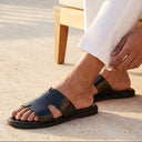 Person wearing black sandals sitting on a bench outdoors