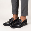Black loafers worn with gray pants on a light background