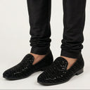 Black sequin loafers worn with black pants on a white background
