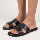 Black sandals worn by a person on a white background