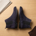 Pair of dark blue suede shoes on a wooden surface