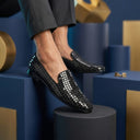 Black woven shoes on a geometric blue and gold background