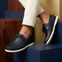 Person wearing navy blue loafers with white soles on a colorful geometric background