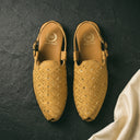 Pair of gold embroidered shoes on a dark textured surface with a white fabric corner.