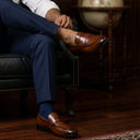 Man sitting in a leather armchair in a room with bookshelves and a globe.