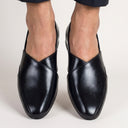 Black leather loafers worn by a person on a light gray background