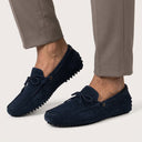 Navy loafers worn with beige pants on a light background