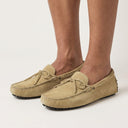 Beige suede loafers worn by a person on a white background