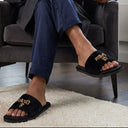 Man in a robe and slippers sitting in a chair holding a mug in a modern living room. comfort home slippers.