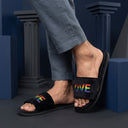 Black slides with rainbow 'LOVE' text worn by a person against a dark blue geometric background