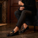 Man in formal attire sitting in a luxurious room with chandeliers. cocktail engagement shoes