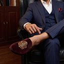 Man in a suit sitting in a leather chair with a bookshelf in the background