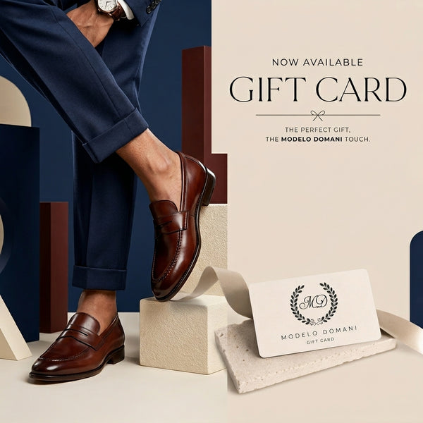 Man wearing brown leather shoes with a Modelo Domani gift card on a beige surface.
