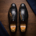 Pair of black leather dress shoes on a wooden surface