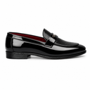 A single black patent leather loafer with a textured leather strap and a small gold-tone logo detail, shown in profile against a white background.